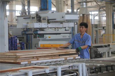 蘭考縣一家家居企業(yè)的生產(chǎn)車間里,工作人員在處理家具板材.jpg